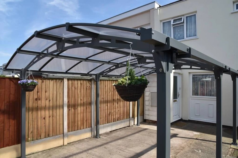 Curved-roof carport canopy on a driveway, installed by Canopies & Shelters Ltd