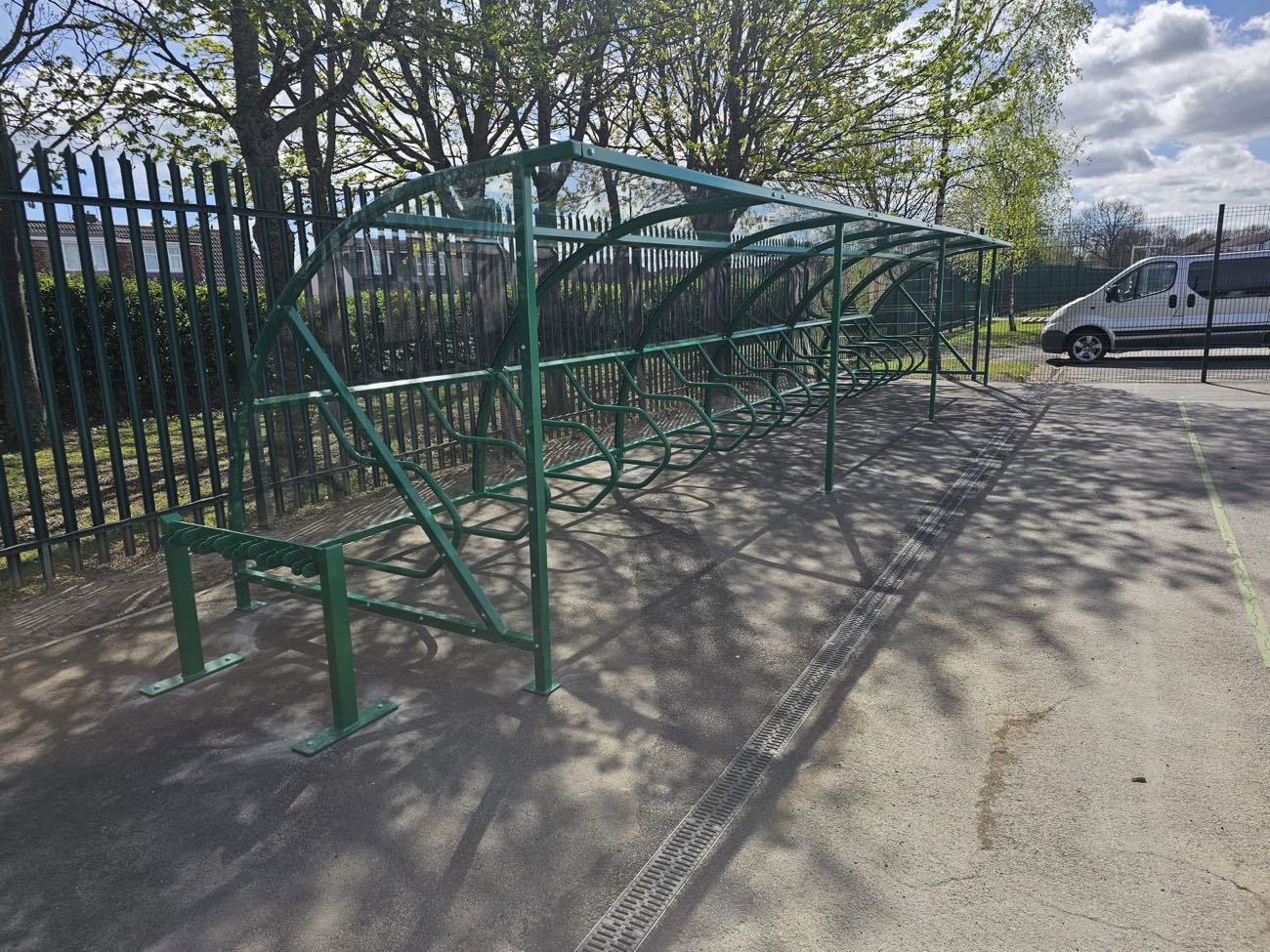 Green steel cycle shelter with a clear roof and cycle stands installed at a school by Canopies & Shelters Ltd