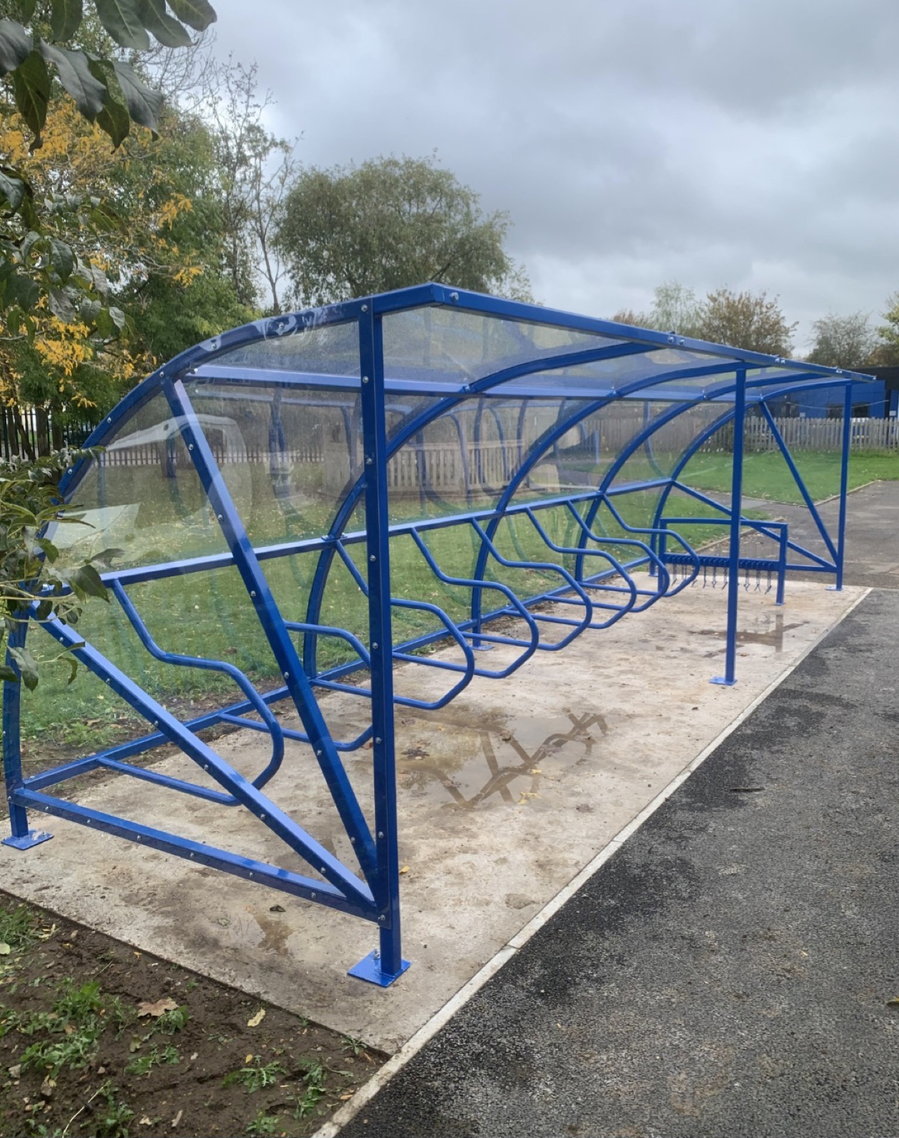 Blue wave-roof cycle shelter on a concrete base