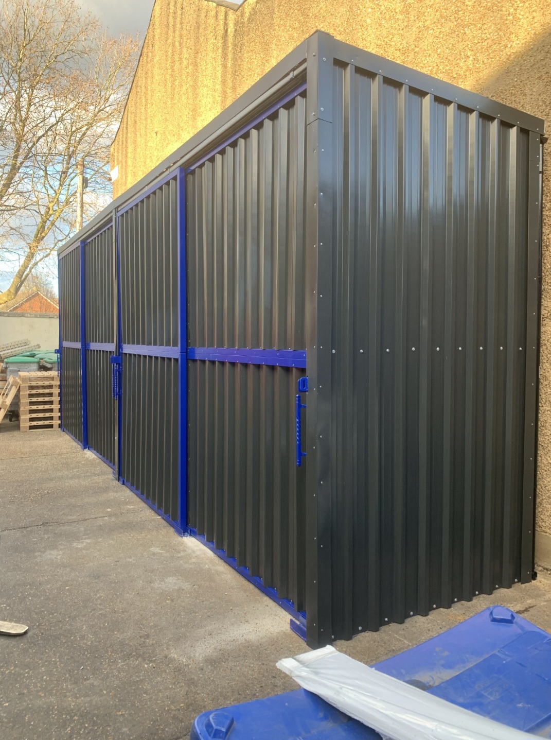 Enclosed warehouse storage shelter with dark corrugated cladding on a blue steel frame and sliding doors closed, in Sheffield